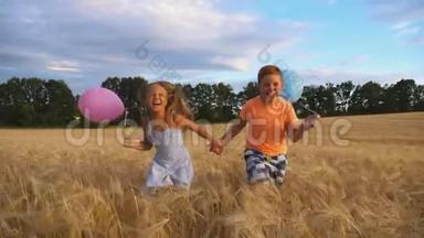几个抱着气球的快乐小孩在麦田里慢跑。 小女孩和小男孩手牵手